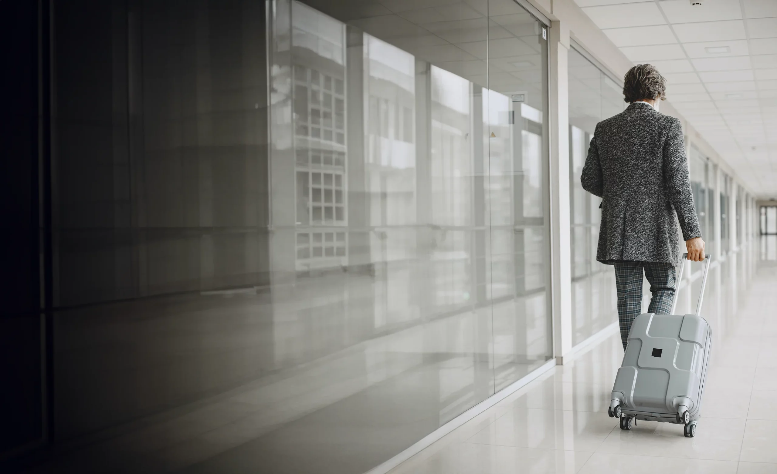 Un homme marche à l'aéroport avec sa valise pour un déplacement professionnel.