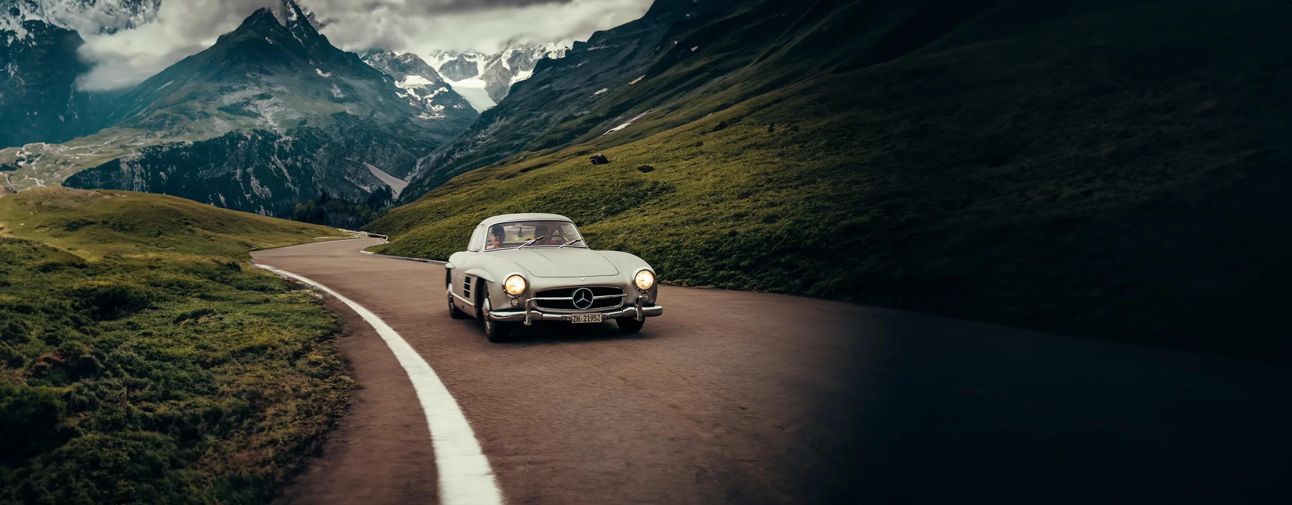 A Mercedes 300 SL driving through a mountain pass in Switzerland.