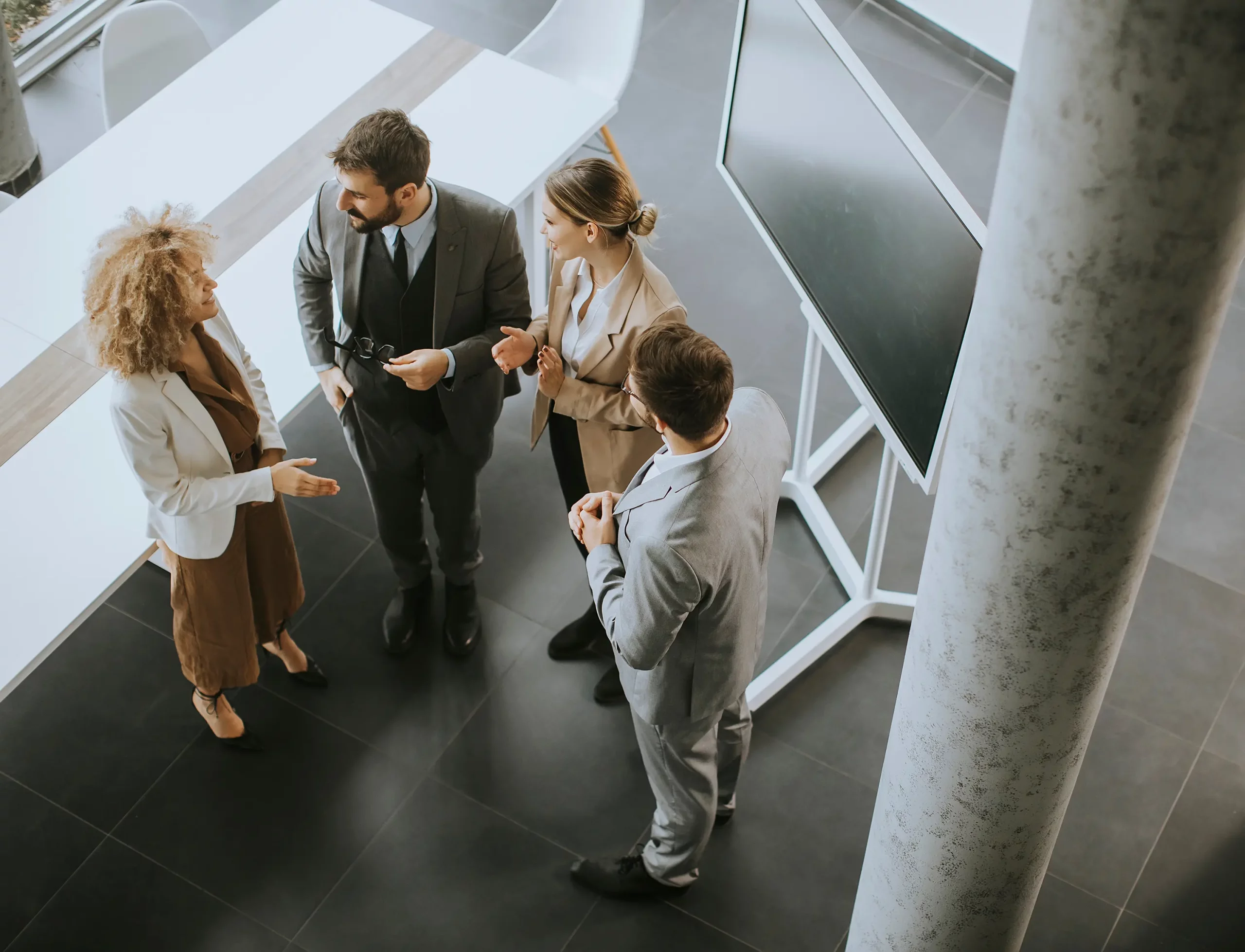 Deux femmes et deux hommes discutent d'un projet dans une salle de conférence.
